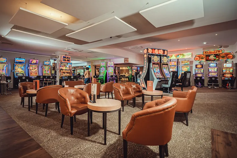 Gaming lounge with slot machines and armchairs at Casino JOA César Palace de Saint-Paul-lès-Dax