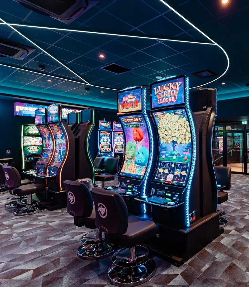 Blue gaming machines beneath geometric ceiling lights at Casino JOA de Saumur