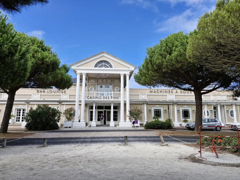 White facade framed by pine trees at Casino JOA Les Pins des Sables d'Olonne
